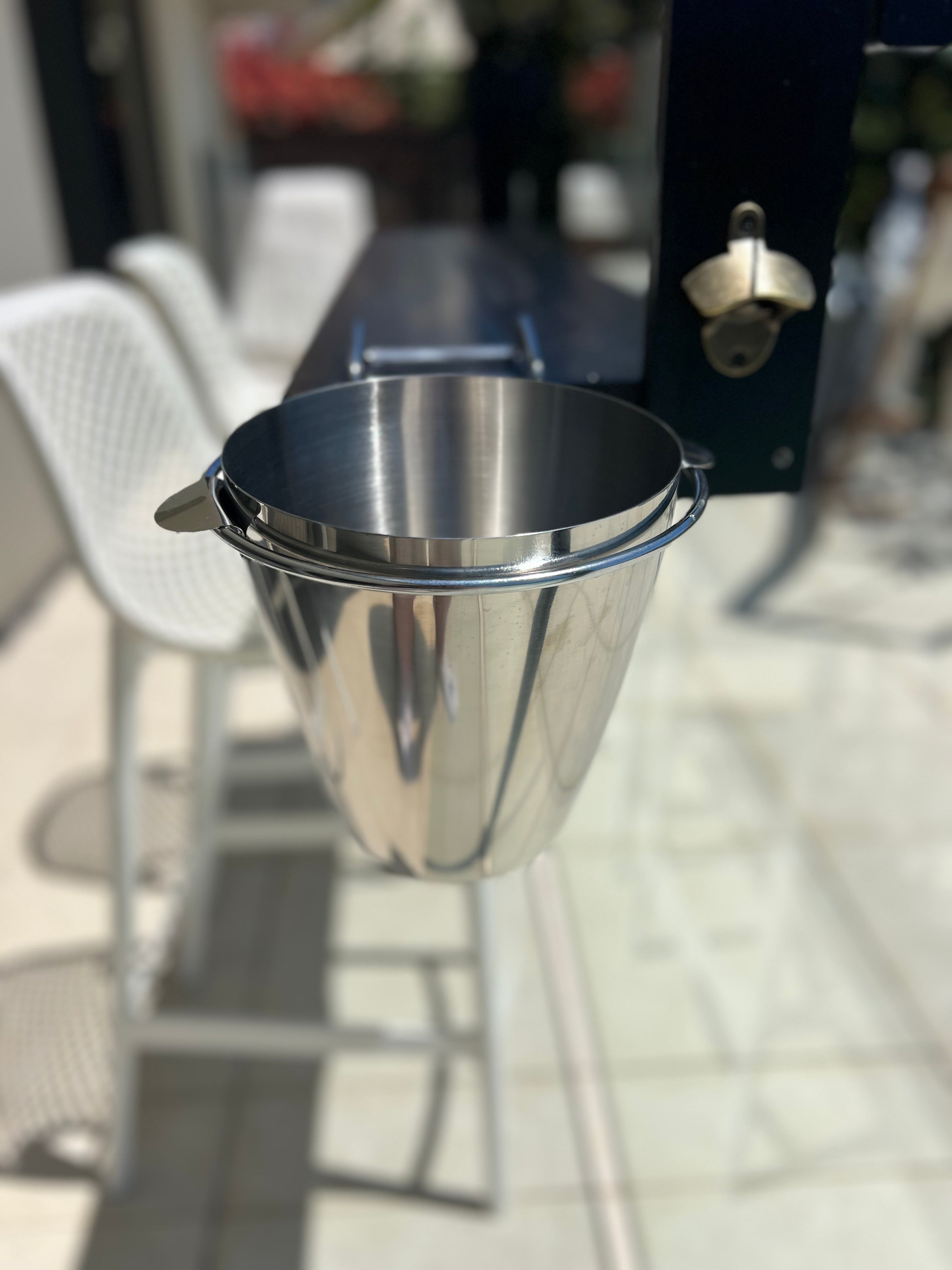 Metal bucket attached to a barbecue grill outdoors